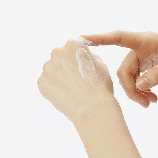 mano sinistra con piccola quantità di crema idratante e che viene spalmata con il dito dell'altra mano 